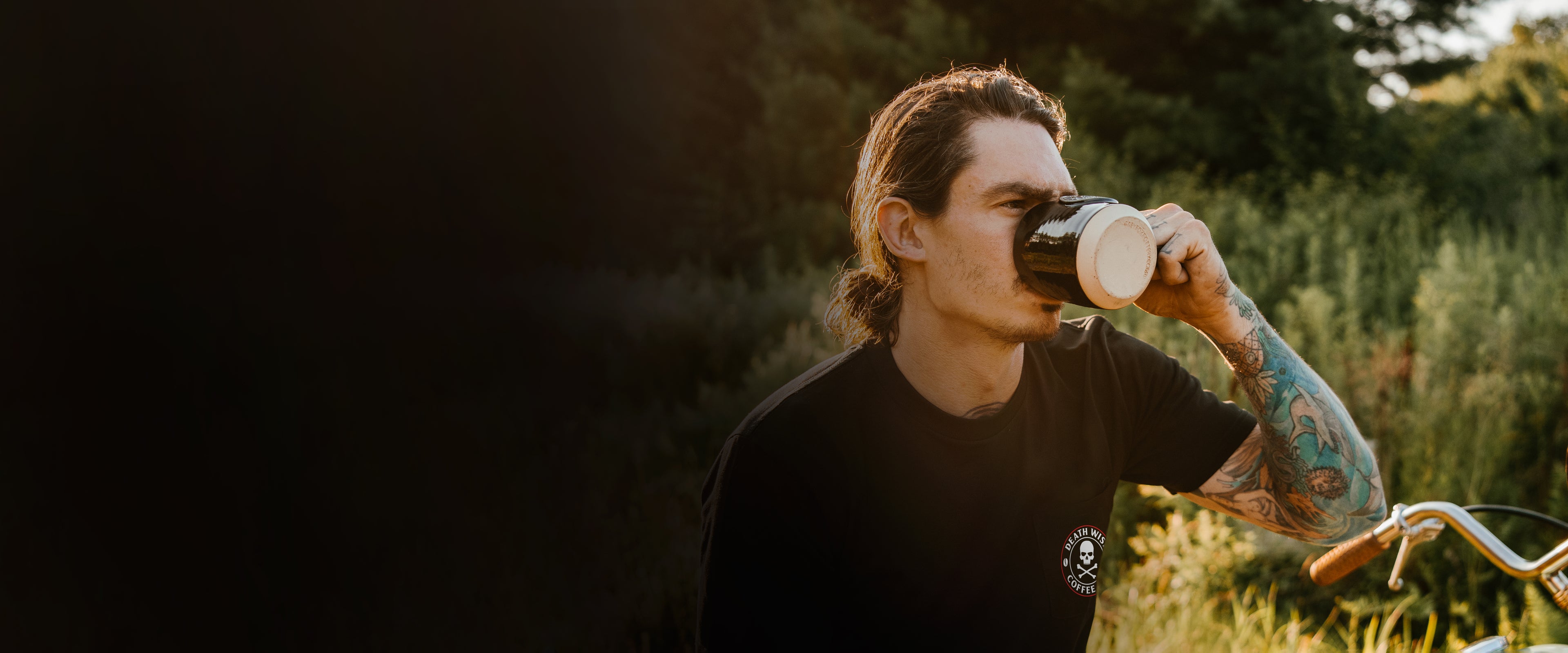 A model drinking from a Death Wish Coffee mug in a Death Wish Coffee shirt.