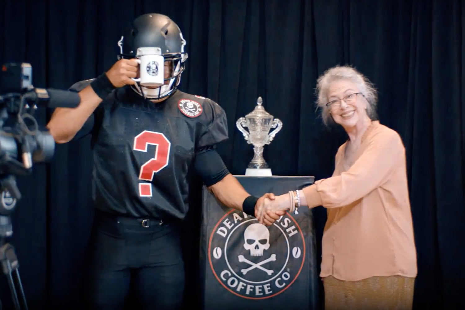 Unknown sponsored athlete drinking Death Wish Coffee at a media conference.
